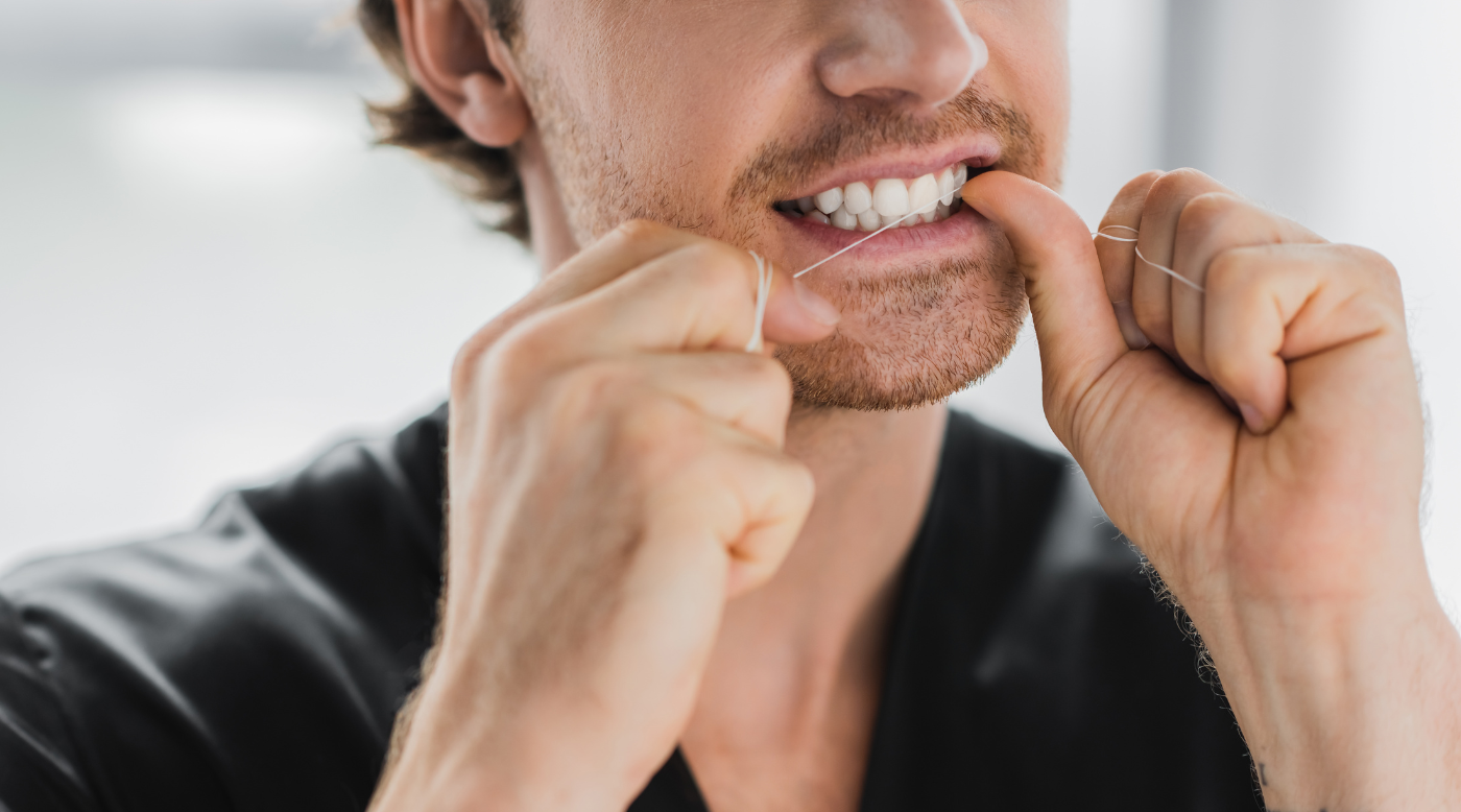 Mann benutzt Zahnseide